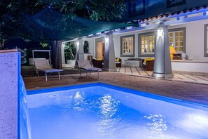 Ein Swimmingpool mit Liegestühlen und einer überdachten Terrasse.