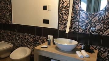 A bathroom with a large sink, two urinals, a toilet, and a mirror.