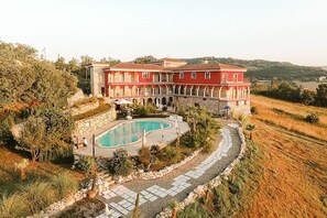 A large, red building with a swimming pool and stone pathways. - Villa Vento dei Cieli (Teora)