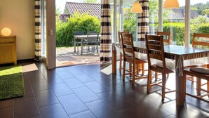 Un espace repas comprenant une table et des chaises, de grandes fenêtres et une vue sur l’extérieur.