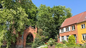 A brick archway, a yellow building, and lush greenery. - Ferienwohnung mit Balkon - Hunde Willkommen Wiesengeflüster (Röbel/Müritz)