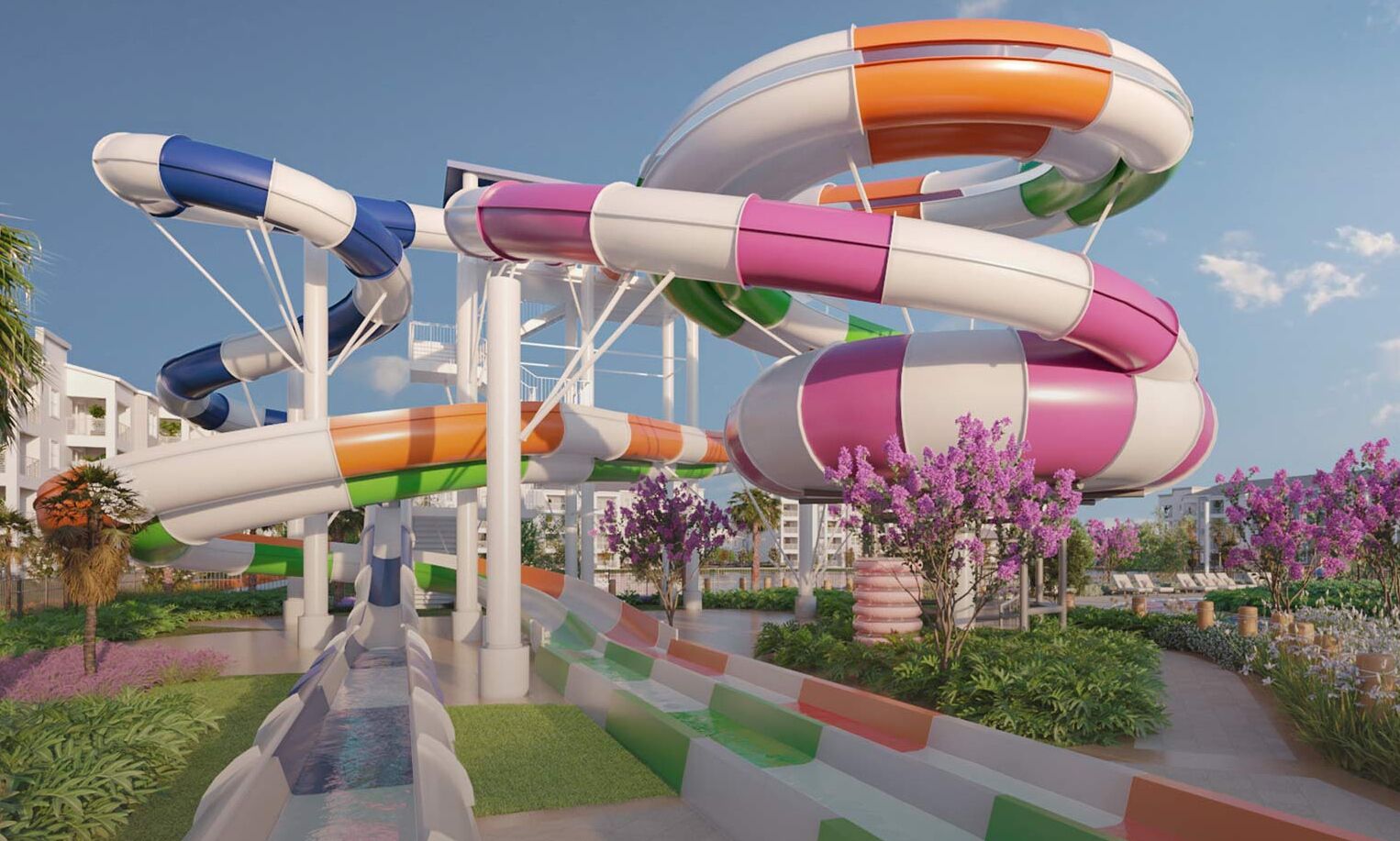 A water park with multiple slides in various colors, surrounded by greenery and flowers.