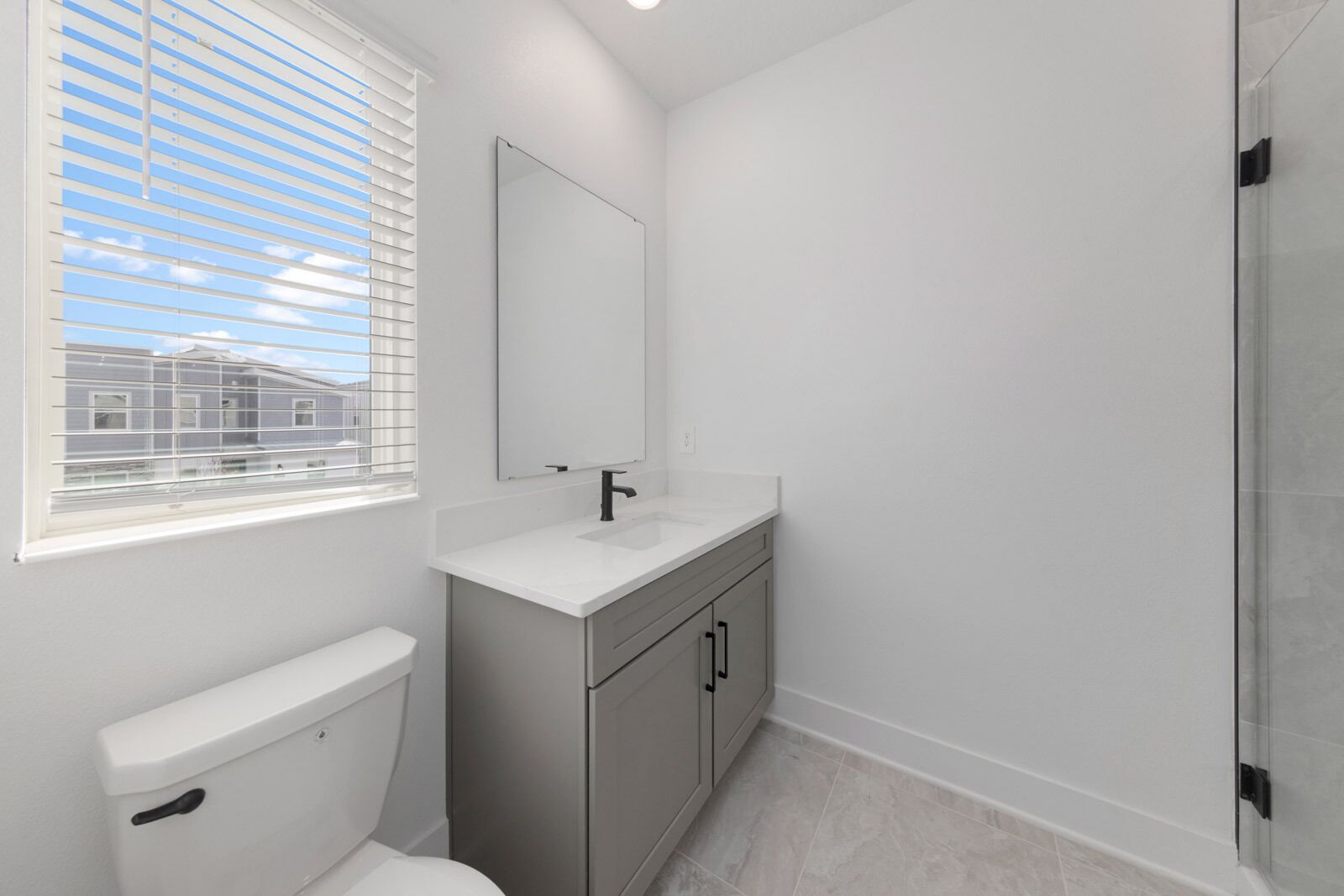 A modern bathroom with a toilet, sink, and mirror.