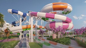 A water park with multiple colorful water slides and a pathway lined with greenery and flowers.