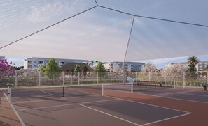 Ein Tennisplatz im Freien mit Netz, umgeben von einem Zaun und Bäumen.