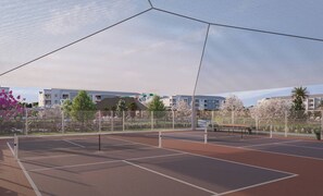 Ein Tennisplatz im Freien mit Netz, umzäunt und von Bäumen gesäumt.