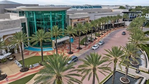 A modern building with a glass facade, palm trees, and a parking area. - Vor5468aa: 4 Bed, Gamer's Paradise, Pool (Orlando)
