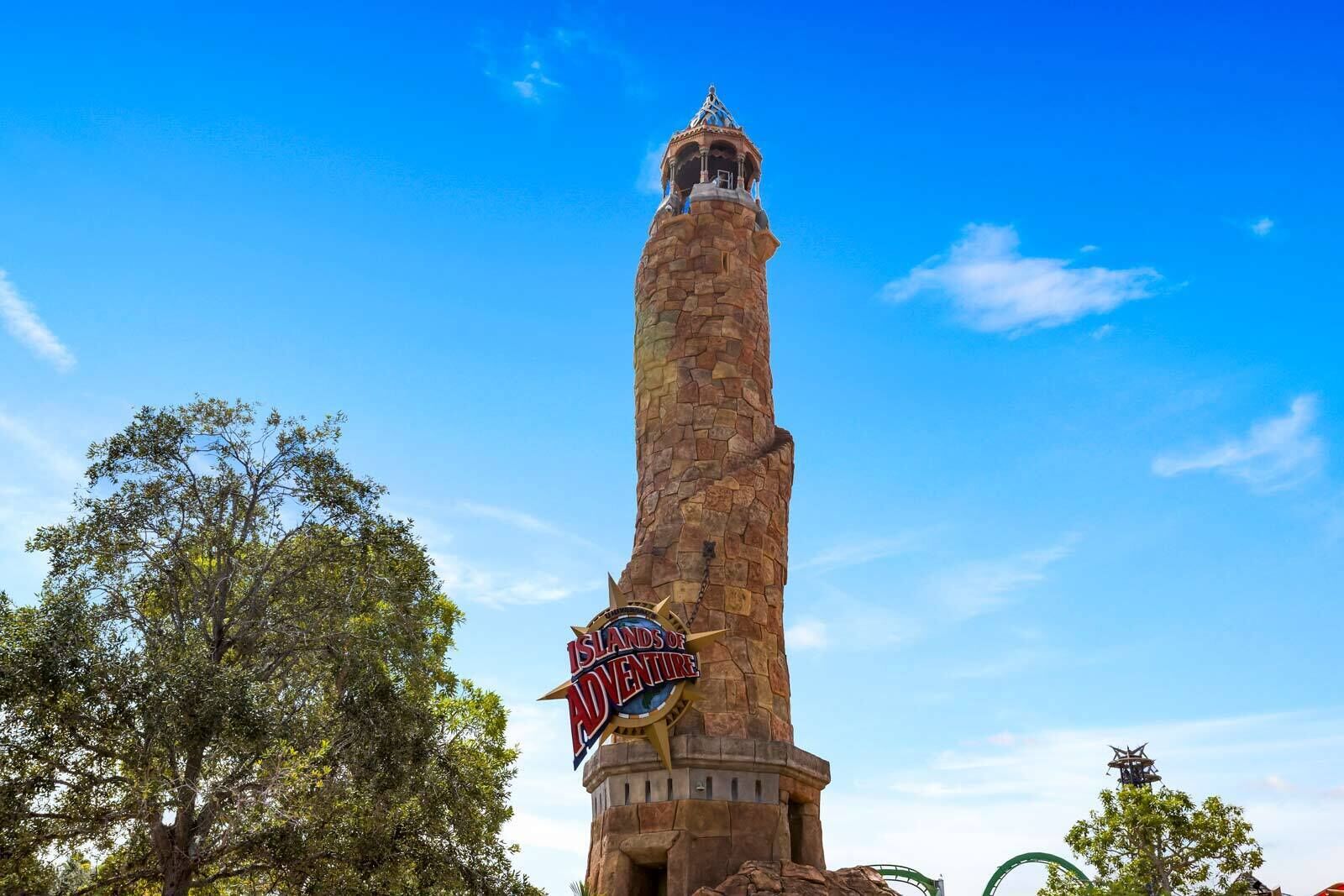 Uma torre de pedra alta com uma placa no topo que diz 'Islands of Adventure'.