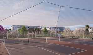 Un court de tennis en plein air, doté d’un filet, entouré d’une clôture et d’arbres.