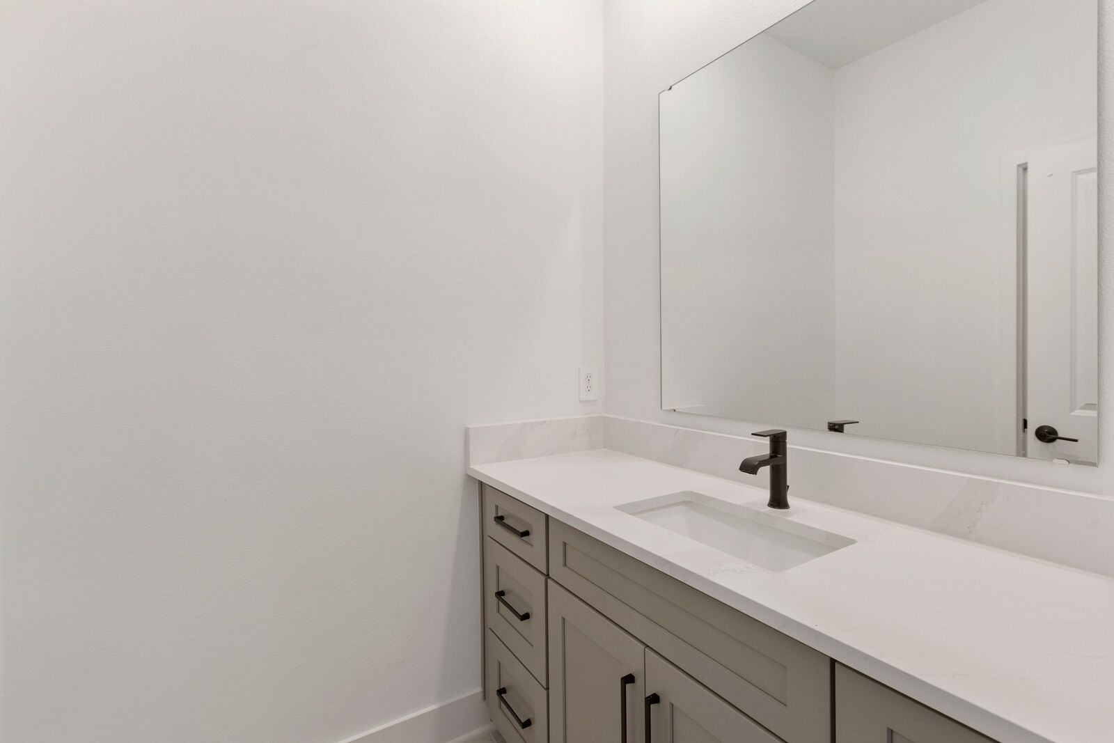 A bathroom with a white sink, a mirror, and a cabinet with drawers.