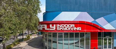 A building with a red and blue facade, featuring a sign that reads "FLY INDOOR SKYDIVING".