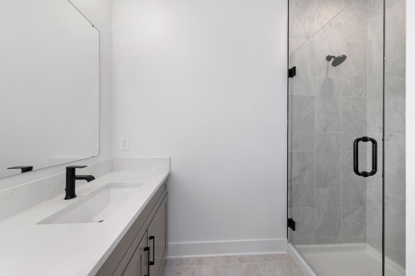A modern bathroom with a white vanity, a glass shower enclosure, and a large mirror.