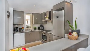 Une cuisine moderne avec des meubles de couleur grise, un four encastré, un four à micro-ondes et un réfrigérateur.