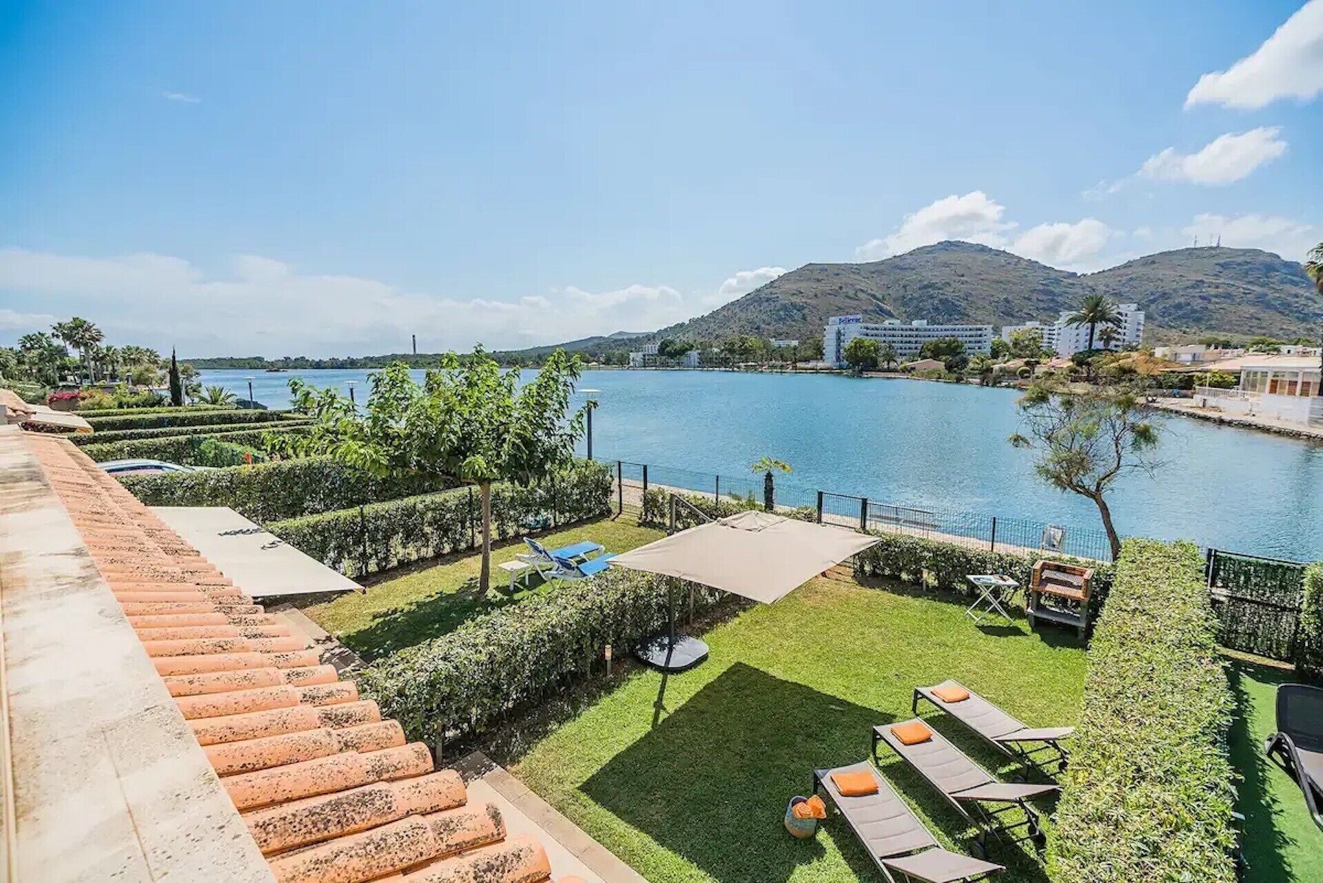 Eine Terrasse mit Seeblick, Liegestühlen und einem gepflegten Rasen.