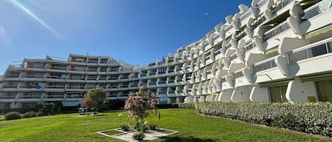 Un hotel moderno con varios balcones y un césped bien cuidado.