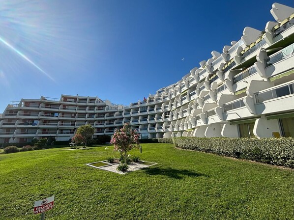 A modern hotel with multiple balconies and a well-maintained lawn.