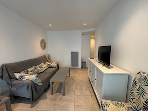 Una sala de estar con un sofá, una mesa de centro, un televisor sobre un mueble bajo y un aparador.