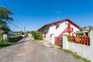 Une route de campagne mène à un bâtiment blanc, doté d’un toit rouge et entouré d’une clôture rouge.