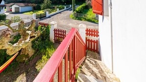 A staircase leading up to a building with a red railing, surrounded by greenery and a fence. - Fully Renovated and Air-Conditioned T3 Apartment in Southern Basque Country and Landes (Tarnos)