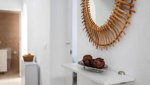 A modern interior with a white wall, a decorative wooden wall hanging, and a small shelf with decorative items. - Casa Carmen (Vejer de la Frontera)