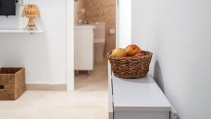 A wicker basket with apples on a white console table in a modern, minimalistic room with a TV and a lamp. - Casa Carmen (Vejer de la Frontera)