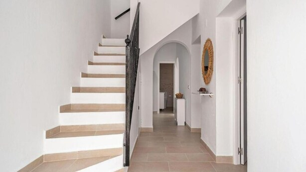 A staircase leading to a landing with a white wall and a mirror. - Casa Carmen (Vejer de la Frontera)