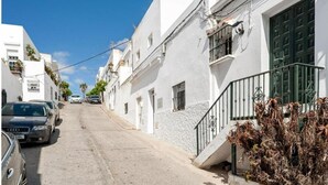 A narrow street lined with white buildings, parked cars, and a clear blue sky. - Casa Carmen (Vejer de la Frontera)