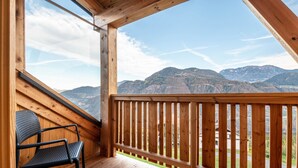 A wooden balcony with a view of mountains, a black chair, and a wooden railing. - Apartment 'Rotwandterhof Bienenstock' with Mountain View, Shared Garden and Wi-Fi (Lengstein)