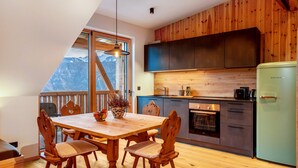 A kitchen with wooden cabinets, a dining table with chairs, and a view of mountains through a large window. - Apartment 'Rotwandterhof Bienenstock' with Mountain View, Shared Garden and Wi-Fi (Lengstein)