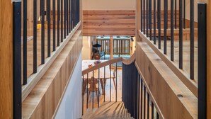 A wooden staircase with metal railings leading to a dining area with a table and chairs. - Apartment 'Rotwandterhof Bienenstock' with Mountain View, Shared Garden and Wi-Fi (Lengstein)
