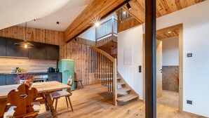 A modern kitchen with wooden accents, a dining area with a wooden table and chairs, and a staircase leading to an upper level. - Apartment 'Rotwandterhof Bienenstock' with Mountain View, Shared Garden and Wi-Fi (Lengstein)