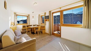 A room with a sofa, dining table, chairs, a TV, and a large window with a mountain view. - Apartment "Unterdurachhof Valentina" with Mountain View, Shared Garden & Wi-Fi (Santa Valburga)