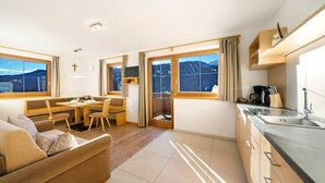 A modern hotel room with a sofa, dining table, and kitchen area. - Apartment "Unterdurachhof Valentina" with Mountain View, Shared Garden & Wi-Fi (Santa Valburga)