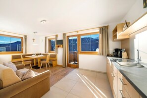 Una habitación de hotel moderna con sofá, mesa de comedor y zona de cocina.
