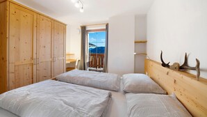 A bedroom with a wooden wardrobe, a bed with white bedding, a wooden headboard, and a view through a window. - Apartment "Unterdurachhof Valentina" with Mountain View, Shared Garden & Wi-Fi (Santa Valburga)