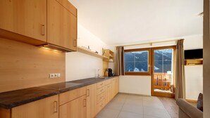 Una cocina moderna con armarios de madera, encimera negra y ventana con vistas a montañas.