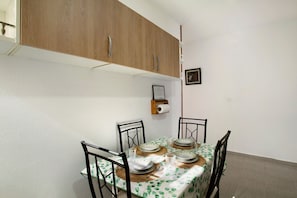 A dining area with a table set for four, wooden cabinets above, and a wall-mounted toilet paper holder.