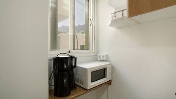 Una cocina con ventana, cafetera y microondas en la encimera.