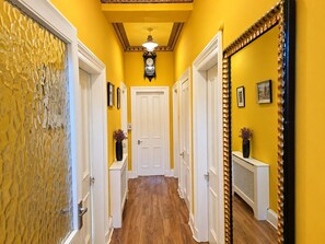 A hallway with yellow walls, white doors, and a wooden floor. - Snug - Fountain Bank Apartment (Helensburgh)