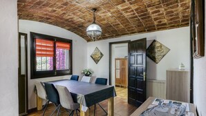 Un espace repas comprenant une table, des chaises, un lustre et une vue sur l’extérieur.