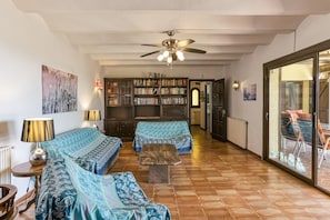 A living room with two sofas, a coffee table, a ceiling fan, and a bookshelf. - Country House 'Casa Gina' with Sea View, Private Terrace and Wi-Fi (Castell d'Aro)