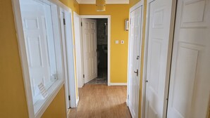 A hallway with wooden flooring, white doors, and yellow walls. - Snug - Colquhoun Square Apartment (Helensburgh)