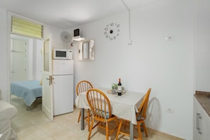 Une cuisine compacte comprenant une table à manger, des chaises, un four à micro-ondes et une horloge murale.