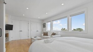 Ein Schlafzimmer mit einem großen Bett, einem Fernseher, einer Couch und einem Fenster mit Blick.