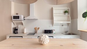 A modern kitchen with white cabinetry, a microwave, a coffee maker, and a wooden table with a decorative object.