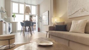 A modern living room with a sofa, a round coffee table, and a dining area with chairs and a table.