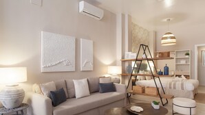 A modern living room with a sofa, coffee table, and side tables. There is a ladder, shelves, and a hanging light fixture.