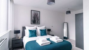 Una habitación de hotel moderna con una cama, dos mesitas de noche, un espejo y una ventana.