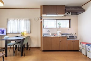Une cuisine compacte avec des meubles en bois, un évier, une cuisinière et un coin repas comprenant des chaises et une table.