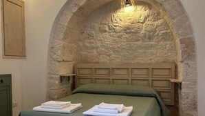 A bedroom with a stone arch, a green bed, and a wooden bedside table. - iCONICO - Authentic Trulli Experience (Cisternino)